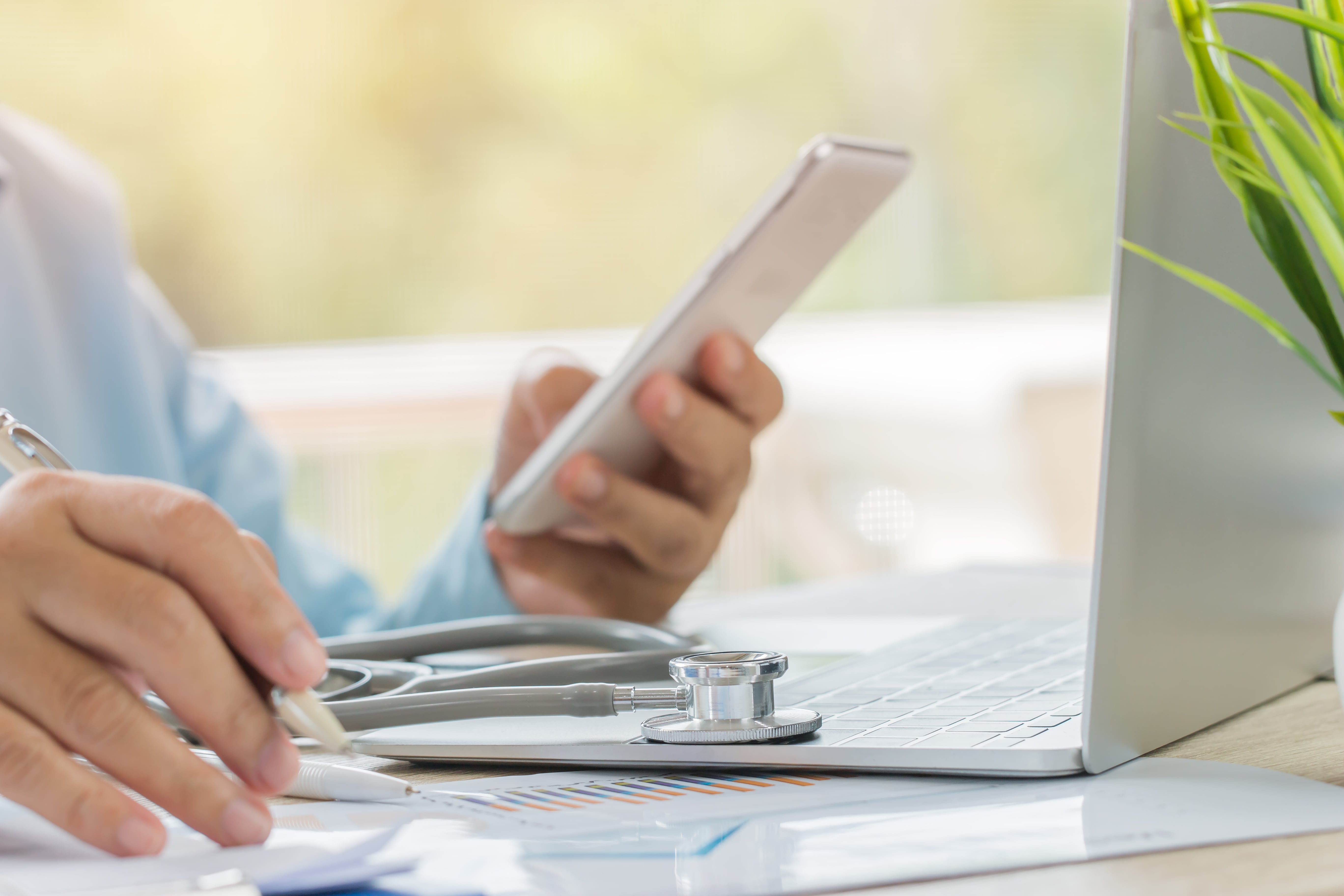 Doctor using phone and laptop for marketing.