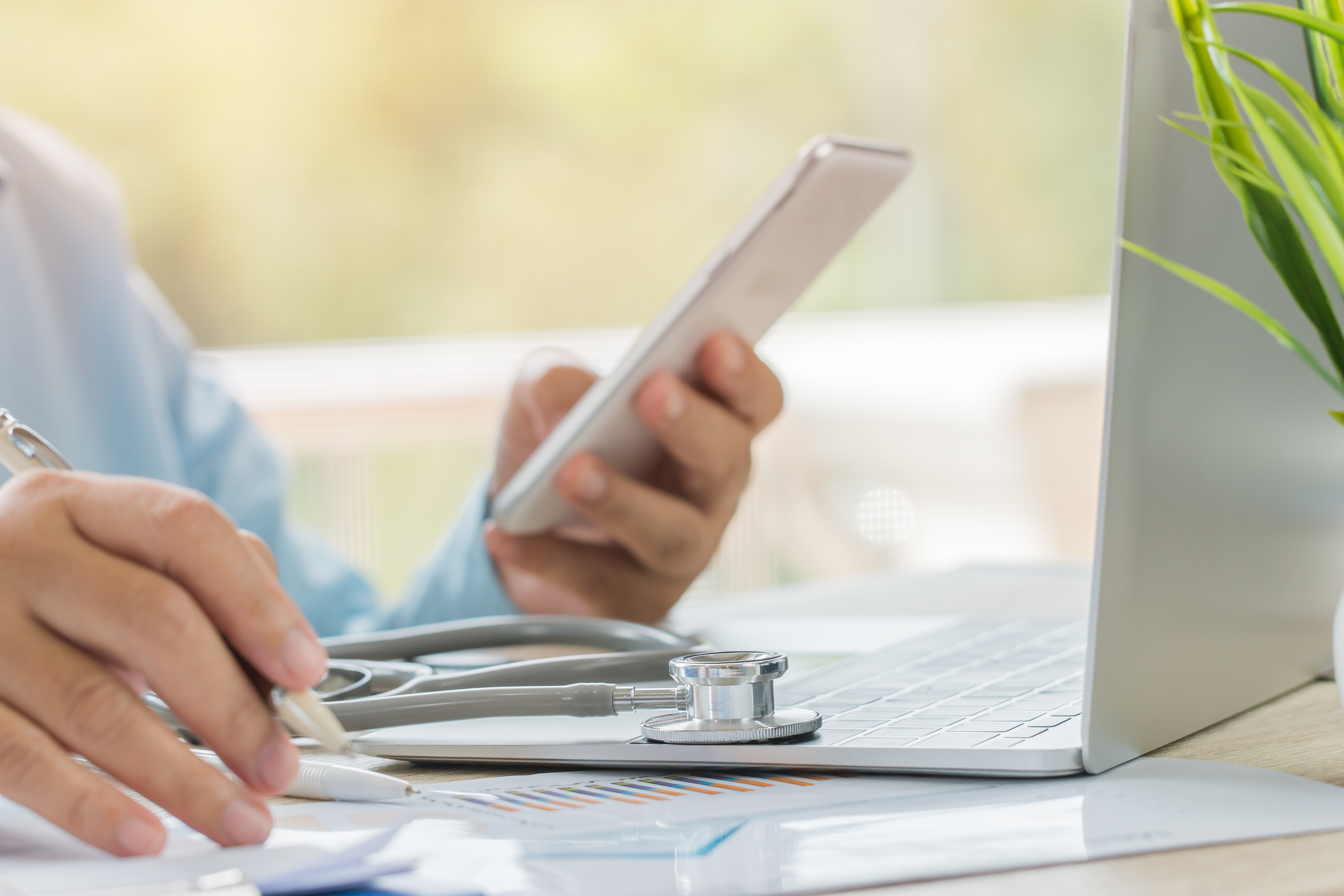 Doctor using phone and laptop for marketing.