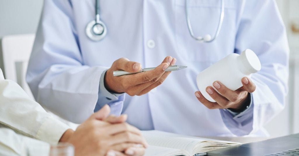 Doctor prescribing medicine to patient or discussing drug with sales rep.