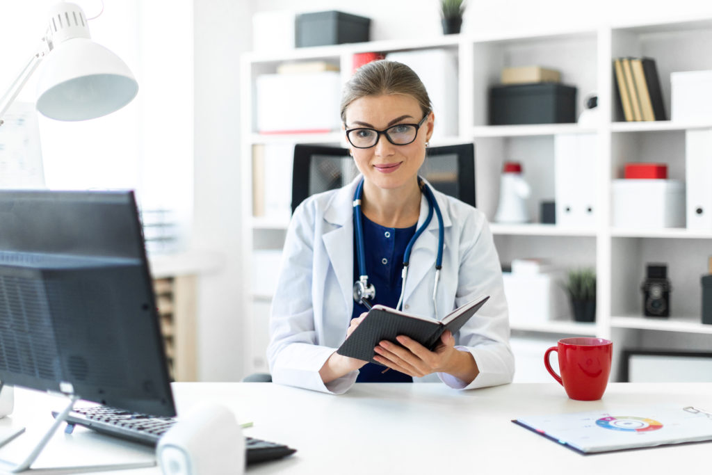 Physician at her desk holding an iPad.