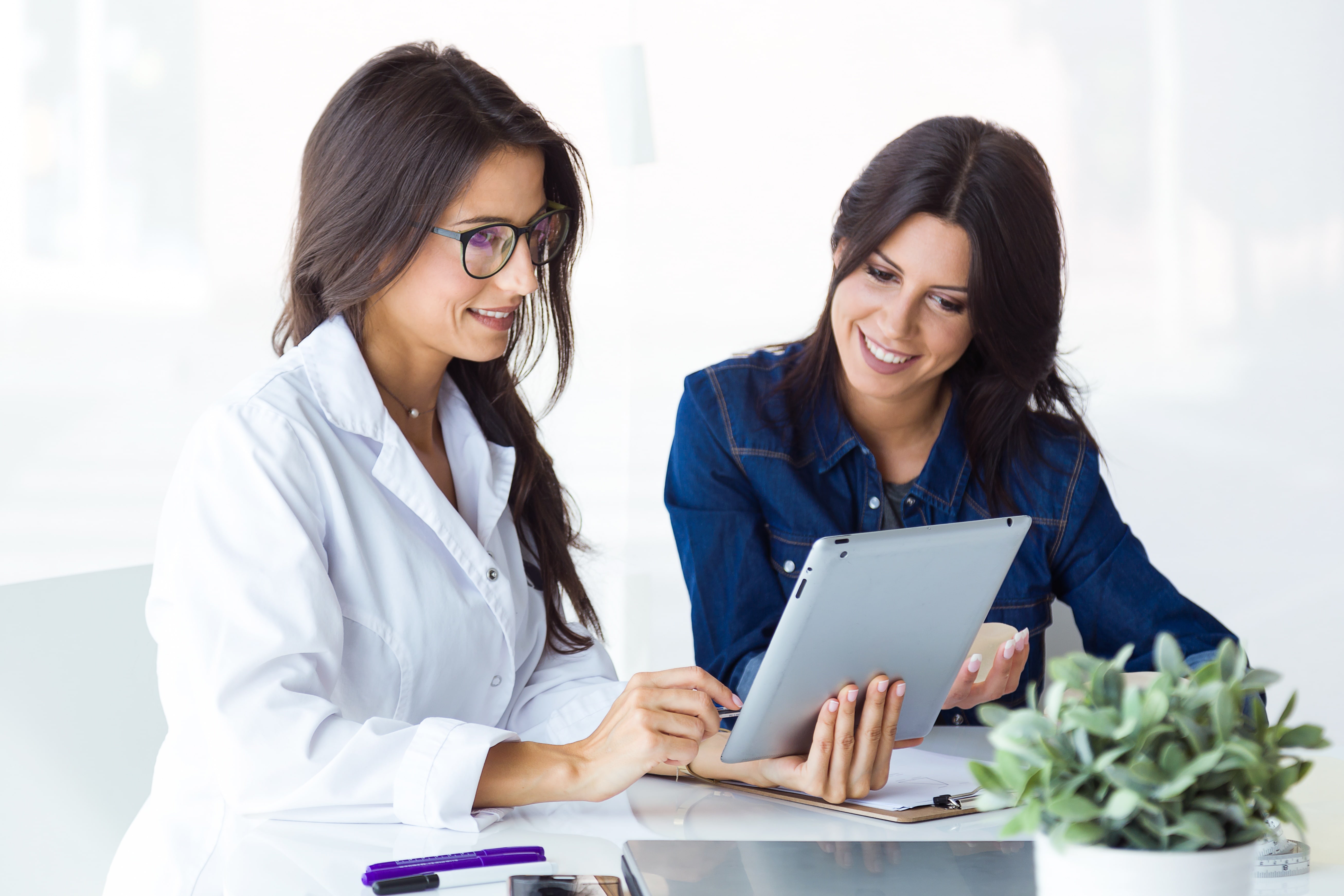 Physician meeting with sales rep discussing over a tablet.