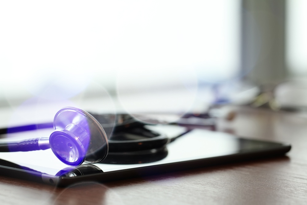 Studio macro of a stethoscope and digital tablet with shallow DOF evenly matched abstract on wood table background copy space-1
